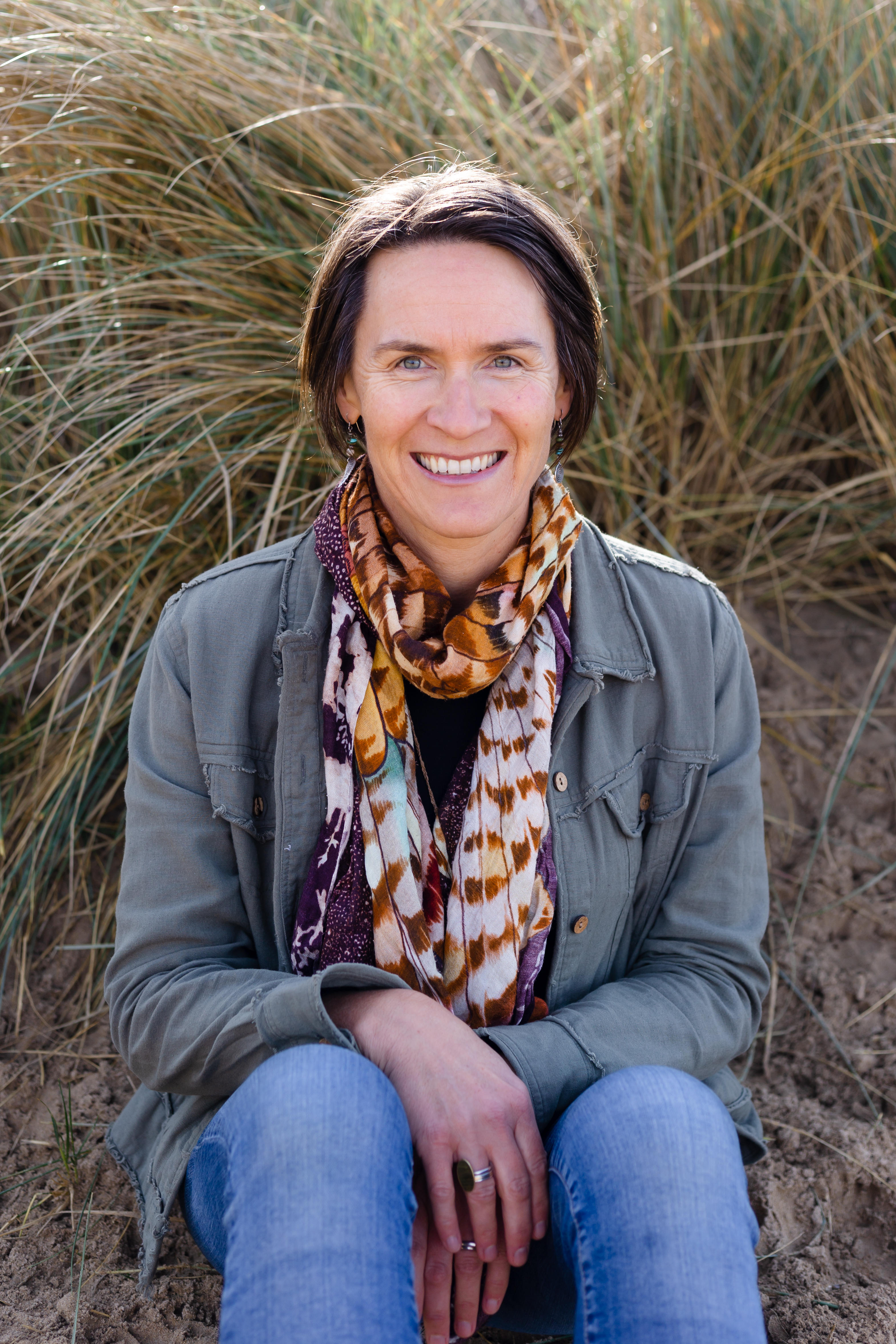 Bev Merrett — founder of Greater Good Co, sitting in the dunes